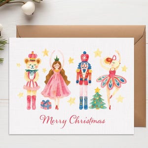 Peut inclure: Carte de Noël à l'aquarelle avec des illustrations d'ours en peluche, de ballerine, de casse-noisette et de danseuse. La carte a une enveloppe marron et l'inscription "Merry Christmas" en script rouge.