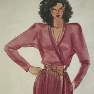 May include: A watercolor fashion illustration of a figure with dark curly hair wearing a long-sleeved, deep mauve wrap dress with a V-neckline and a wide, light brown belt featuring a central buckle. The garment has structured shoulders.