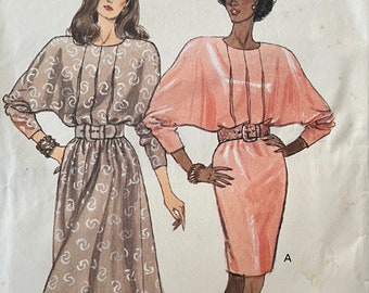 May include: A sewing pattern for two dresses. The dress on the left is brown with a white pattern and the dress on the right is pink. The pattern is labeled "ST&EASY" and "VERY EASY/TRES FACILE".