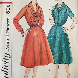 May include: Vintage Simplicity sewing pattern number 2661 for a half-size slenderette dress. The pattern includes two styles: a red dress with a bow and a teal dress with a polka dot pattern. The pattern is for size 16 1/2 and bust 37.
