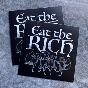 May include: Two black square stickers with white text and illustrations. The text reads "Eat the RICH" in a stylized font. Below the text is a line of dancing mice.