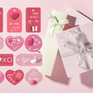 Puede incluir: Un conjunto de etiquetas de regalo y cajas de regalo para el D&iacute;a de San Valent&iacute;n. Las etiquetas tienen varias formas y colores, con frases como "Te amo" y "s&eacute; m&iacute;o". Las cajas de regalo son rosas y blancas, atadas con cintas.