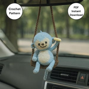 May include: A crocheted blue monkey hanging from a brown swing, with a light beige belly and face. The monkey is smiling and holding a yellow banana. Text on the image reads "Crochet Pattern" and "PDF Instant Download".