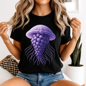 May include: Black t-shirt with a detailed purple jellyfish graphic. The jellyfish design features a rounded bell and long, flowing tentacles. The illustration is centrally placed on the shirt, offering a bold and eye-catching aesthetic.