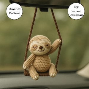 Puede incluir: Un perezoso de ganchillo en un columpio, colgado del espejo retrovisor de un coche. El perezoso es de color beige y crema, con los ojos cerrados y una expresión sonriente. El columpio es marrón. El texto dice "Crochet Pattern" y "PDF Instant Download."
