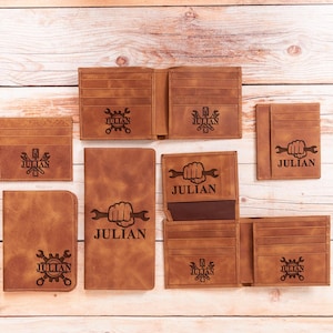 May include: A collection of brown leather wallets, cardholders, and a notebook. Each item features a personalized design with the name "JULIAN" and a mechanic-themed graphic. The items are arranged on a light wooden surface.