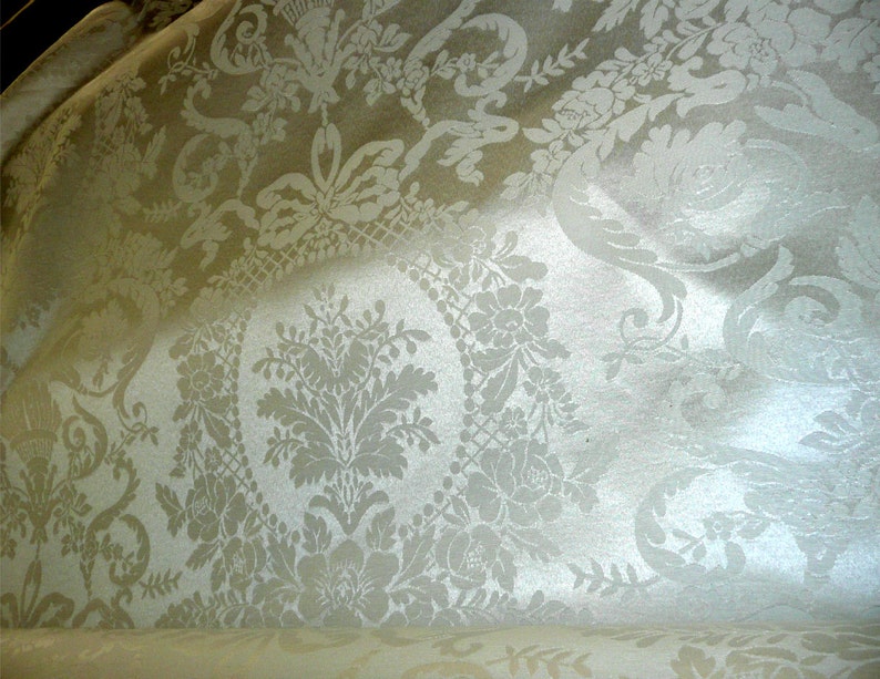 May include: White fabric with a damask pattern featuring a repeating floral design.