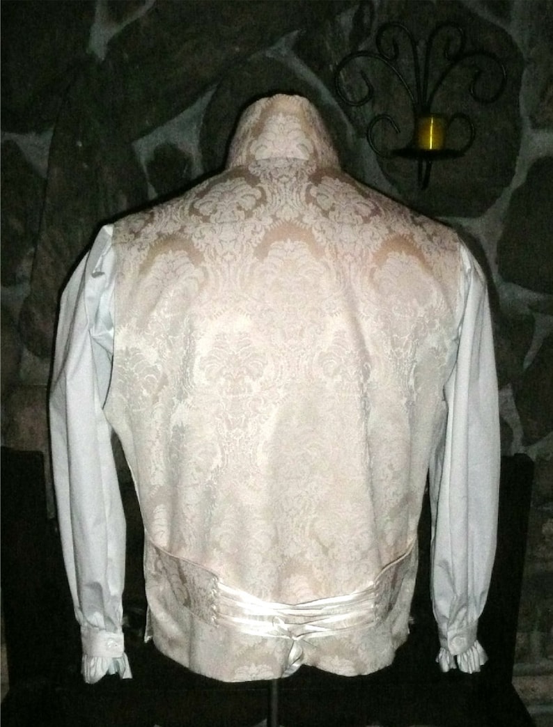 May include: A white brocade vest with a white satin back and a white shirt with long sleeves and ruffled cuffs.