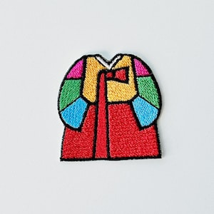 Könnte beinhalten: Gestickter Aufnäher mit einem farbenfrohen, stilisierten Design, das an einen traditionellen koreanischen Hanbok erinnert. Der Aufnäher hat eine rote Basis mit einem langen Mittelstreifen und ist mit schwarzen Nähten eingefasst. Der obere Teil ist mit Blau, Grün, Gelb und Rosa segmentiert.