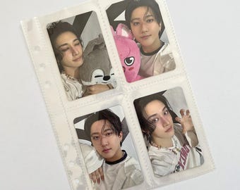 May include: Four rectangular photo cards displayed in a clear plastic binder sleeve. The cards feature portraits of two individuals, one holding a grey plush toy and another holding a pink plush toy, with various poses and casual white clothing.