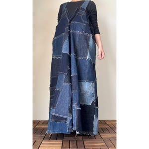 Puede incluir: Vestido de peto vaquero patchwork en varios tonos de azul. El vestido presenta una parte superior de peto con tirantes ajustables y una falda larga y fluida. Las piezas de mezclilla están cosidas juntas en un patrón aleatorio.