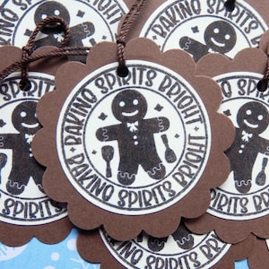 May include: Brown scalloped-edge gift tags with a circular design featuring a gingerbread man and the text "BAKING SPIRITS BRIGHT". The tags have a brown string for hanging.