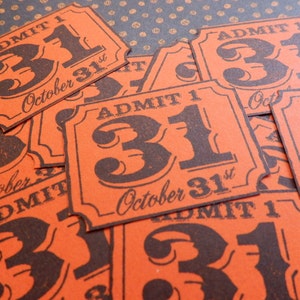 May include: Orange Halloween-themed tickets with the text "ADMIT 1" and "31 October 31st" in black. The tickets have a vintage design and are scattered across a patterned surface, evoking a festive atmosphere.