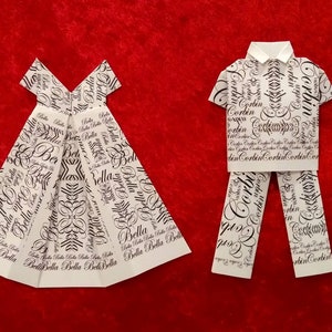 May include: Two origami figures, a dress and a shirt and pants, made from white paper with black text patterns. The dress has the word "Bella" repeated on it. The shirt and pants have the word "Corbin" repeated on them.