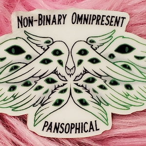 May include: A white sticker with green wings and eyes. The sticker has the text "NON-BINARY OMNIPRESENT" at the top and "PANSOOPHICAL" at the bottom.
