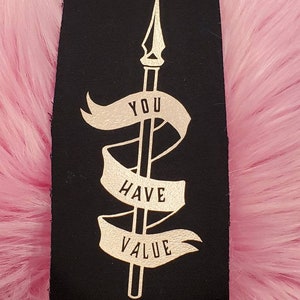 May include: Black fabric patch with gold lettering that reads "You Have Value" and a gold spear design.
