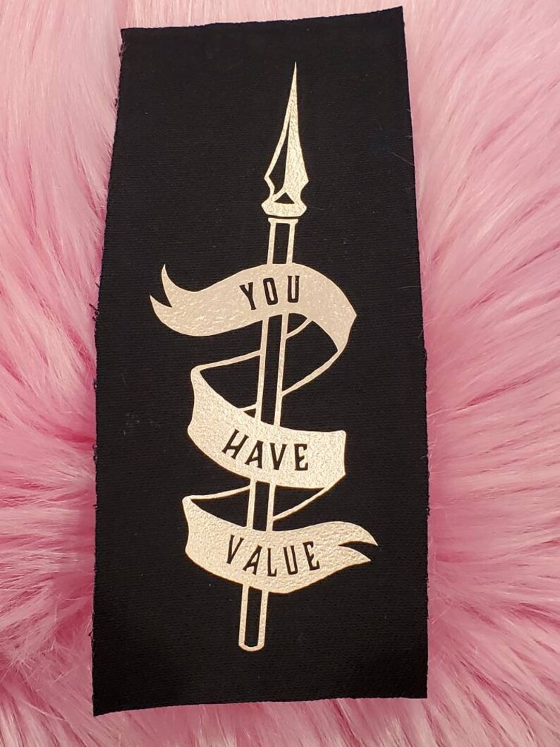 May include: Black fabric patch with gold lettering that reads "You Have Value" and a gold spear design.