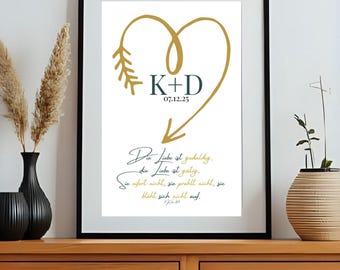 Puede incluir: Impresión enmarcada con borde negro. Presenta un diseño de corazón y flecha dorados, con las iniciales "K+D" y la fecha "07.12.25". Debajo, una elegante escritura dice "Die Liebe ist geduldig, die Liebe ist gütig..."