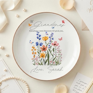 Op de afbeelding: Witte keramische plaat met een gouden rand, met een bloemenontwerp met vlinders en de tekst "If Grandmas were flowers I'd pick you. Love, Sarah." Bruiloft cadeau.