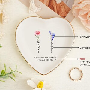 May include: A heart-shaped white ceramic trinket dish with a gold-toned rim. The center features two watercolor-style floral illustrations, each labeled with the name Dallas in black script, and the text IF FRIENDS WERE FLOWERS I WOULD PICK YOU.