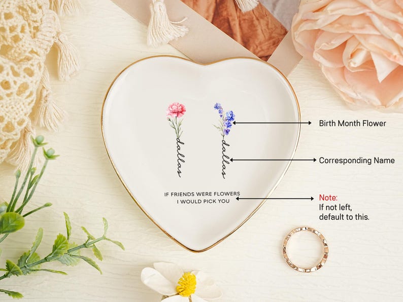 May include: A heart-shaped white ceramic trinket dish with a gold-toned rim. The center features two watercolor-style floral illustrations, each labeled with the name Dallas in black script, and the text IF FRIENDS WERE FLOWERS I WOULD PICK YOU.
