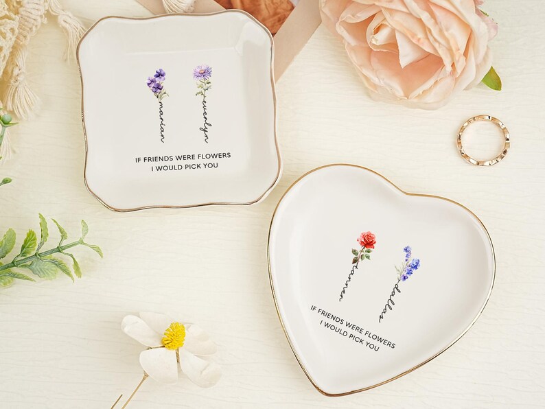 May include: Two white ceramic trinket dishes with gold-toned rims. One dish is square with rounded corners, the other is heart-shaped. Both feature floral illustrations, personalized names, and the text IF FRIENDS WERE FLOWERS I WOULD PICK YOU.