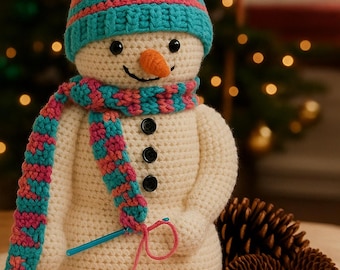 Peut inclure: Bonhomme de neige crocheté avec un chapeau et une écharpe rayés bleus et roses. Le bonhomme de neige a un nez en carotte et des yeux et une bouche en boutons noirs. Une pelote de laine et un crochet sont à côté. Décoration hivernale.