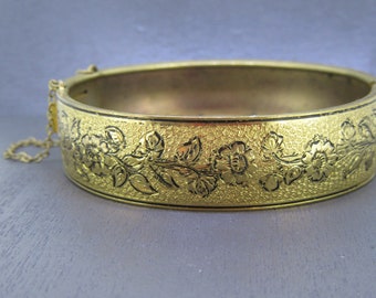 Bracelet vintage avec charnière dorée de 7 po. sur motif floral doré et détails en émail noir