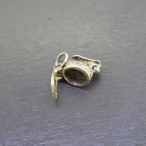 Pu&ograve; includere: Un piccolo ciondolo color oro a forma di brocca in miniatura. Il ciondolo presenta dettagli intricati attorno al bordo e al manico. Il coperchio della brocca &egrave; aperto, rivelando l'interno. Il ciondolo &egrave; progettato per essere attaccato a una collana o un braccialetto.