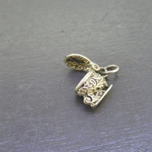 Pu&ograve; includere: Un piccolo ciondolo color argento con un design ornato. Il ciondolo sembra essere una tazza e un piattino in miniatura, con dettagli a volute. Il ciondolo &egrave; probabilmente in metallo ed &egrave; sospeso da un piccolo anello.