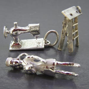 Pu&ograve; includere: Tre ciondoli d'argento: una macchina da cucire, una piccola scala e una figura sdraiata. Il ciondolo della macchina da cucire ha un design dettagliato. La scala &egrave; una versione in miniatura. La figura &egrave; sdraiata con le braccia e le gambe distese.