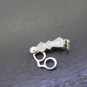Pu&ograve; includere: Una chiusura per gioielli color argento con la scritta incisa "LOVE'S BLIND". La chiusura presenta un design unico a forma di montagna e due anelli circolari. &Egrave; progettata per fissare i gioielli.