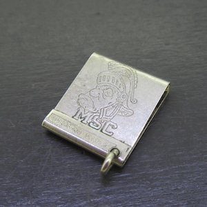 Pu&ograve; includere: Clip per banconote color argento con un'incisione dettagliata di un volto con elmo e le lettere "MSC". Sono visibili anche le parole "STERLING SILVER". &Egrave; attaccato un piccolo anello.