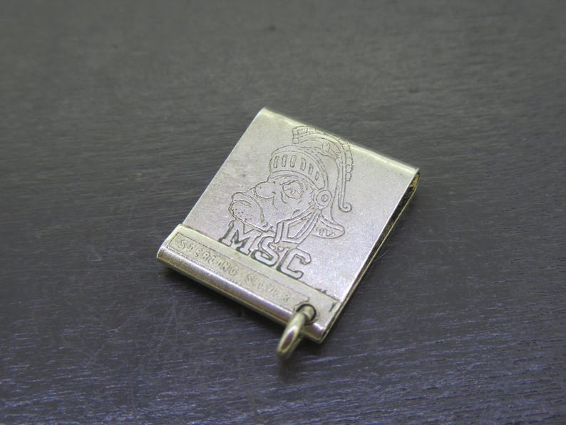 Pu&ograve; includere: Clip per banconote color argento con un'incisione dettagliata di un volto con elmo e le lettere "MSC". Sono visibili anche le parole "STERLING SILVER". &Egrave; attaccato un piccolo anello.