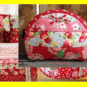 May include: A red and pink fabric pouch with a floral pattern and a bow. The pouch is made of patchwork fabric and has a zipper closure. The pouch is sitting on a wooden surface. The text "JAMIESQUILTING" is visible on the bottom of the image.
