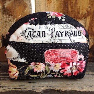 Może przedstawiać: Czarno-biała kosmetyczka z zamkiem błyskawicznym. Kosmetyczka ma kwiatowy wz&oacute;r i nadrukowany tekst "CACAO-PAYRAUD".