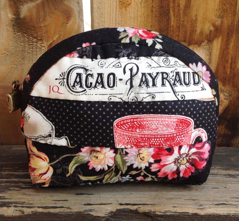 Może przedstawiać: Czarno-biała kosmetyczka z zamkiem błyskawicznym. Kosmetyczka ma kwiatowy wz&oacute;r i nadrukowany tekst "CACAO-PAYRAUD".