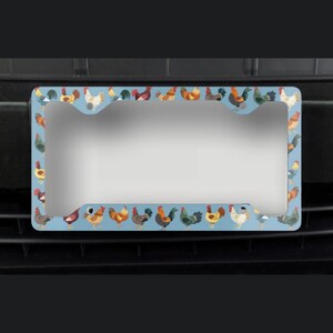 Pode incluir: Um porta-chapas azul com uma borda de galos coloridos. O porta-chapas &eacute; projetado para se ajustar a uma placa de licen&ccedil;a padr&atilde;o portuguesa.