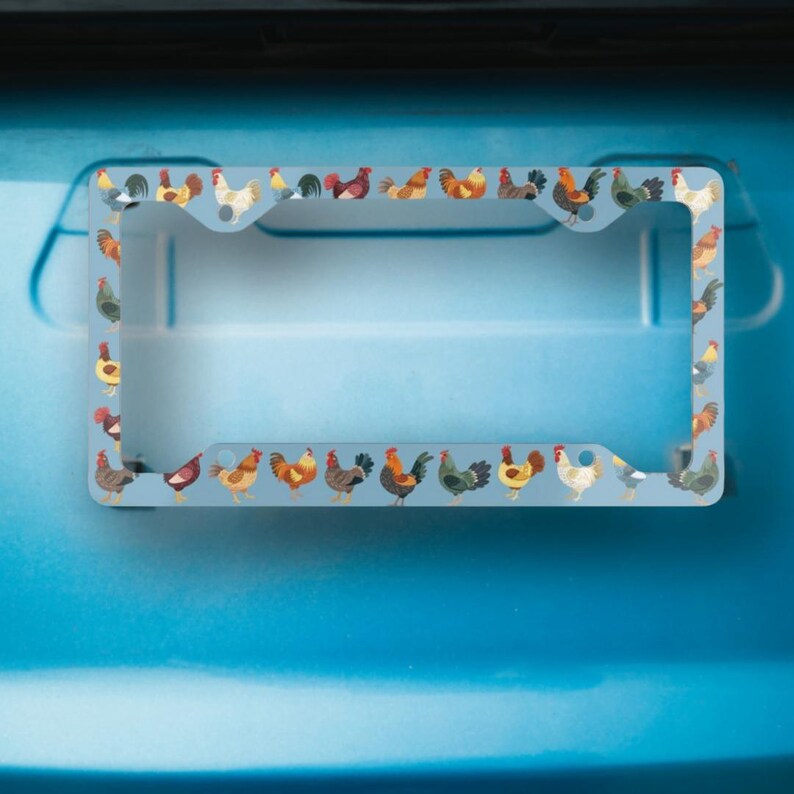 Pode incluir: Uma moldura de placa de carro prateada com uma borda de galos coloridos. A moldura &eacute; projetada para se ajustar a uma placa padr&atilde;o portuguesa.