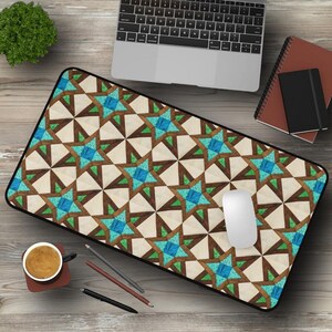 May include: A geometric patterned mouse pad with a brown, white, and blue design. The mouse pad is on a wooden surface with a laptop, a notebook, and a cup of coffee.