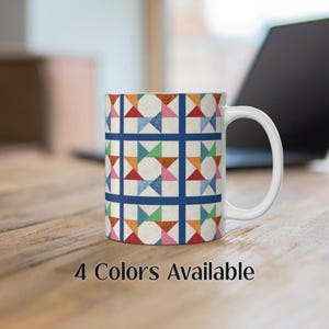 May include: White ceramic mug with a colorful geometric pattern. The pattern features a repeating design of squares with triangles and stars in shades of blue, green, orange, pink, and red. The text "4 Colors Available" is printed below the mug.