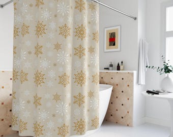 Puede incluir: Una cortina de ducha beige con un patrón repetido de copos de nieve dorados y blancos. La cortina cuelga en un baño con una bañera blanca. Los copos de nieve varían en tamaño y diseño, creando un tema invernal.