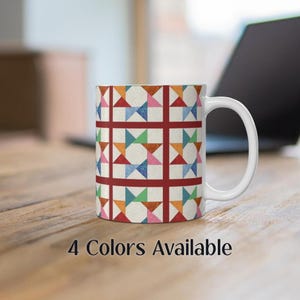 May include: White ceramic mug with a geometric pattern in shades of red, orange, blue, green, and pink. The pattern is a repeating design of stars and squares.  4 Colors Available.
