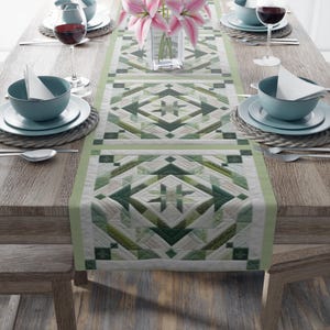 May include: A green and white quilted table runner with a geometric pattern. The runner is on a wooden table with two place settings on each side.