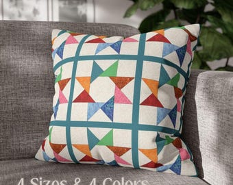 Puede incluir: Una almohada decorativa con un patrón geométrico que presenta un mosaico de triángulos rojos, naranjas, rosas, verdes y azules sobre un fondo blanco. La almohada tiene un borde azul turquesa.