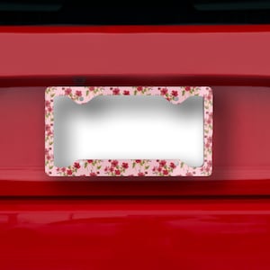 Op de afbeelding: Een roze en rode bloemen kentekenplaathouder met een zilveren metalen frame. De houder is ontworpen om te passen op een standaard Nederlands kenteken.