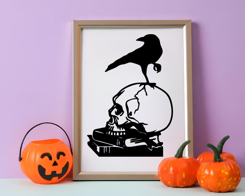 May include: A framed black and white print featuring a skull with a raven perched on top. The skull rests on a stack of books. A jack-o'-lantern bucket and pumpkins are in the foreground, creating a Halloween theme.