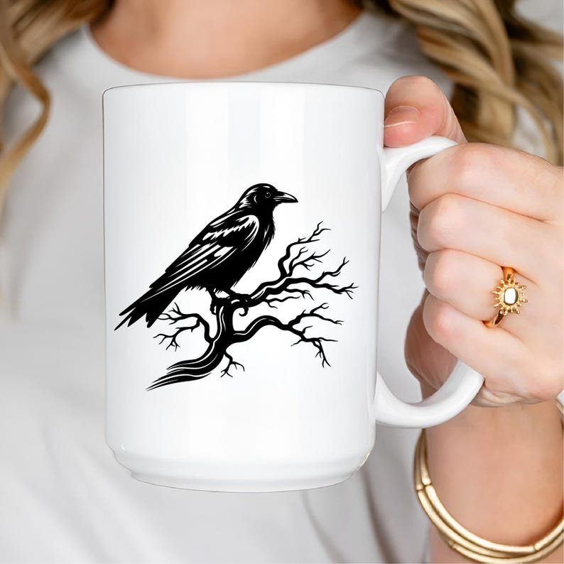 May include: White ceramic mug featuring a black illustration of a raven perched on a tree branch. The raven is detailed with visible feathers and sits on a bare, twisted branch. The mug has a large handle.