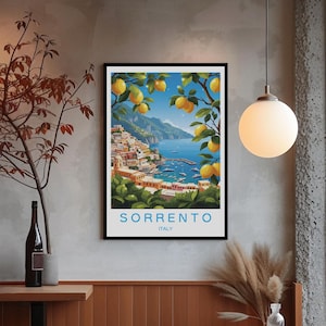 以下が含まれることがあります： イタリアの海岸沿いの町のシーンを描いた、額入りのアートプリント。カラフルな建物、青い海、レモンの木がある丘の上の村を描いています。「SORRENTO」の文字が下部に印刷され、その下に「ITALY」と書かれています。