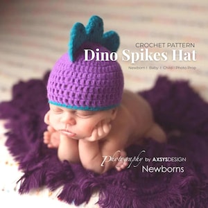 May include: A newborn baby wearing a purple crochet Dino Spikes hat with teal spikes, lying on a purple blanket. The hat has a teal brim. The image includes the text "CROCHET PATTERN Dino Spikes Hat Newborn | Baby | Child | Photo Prop".